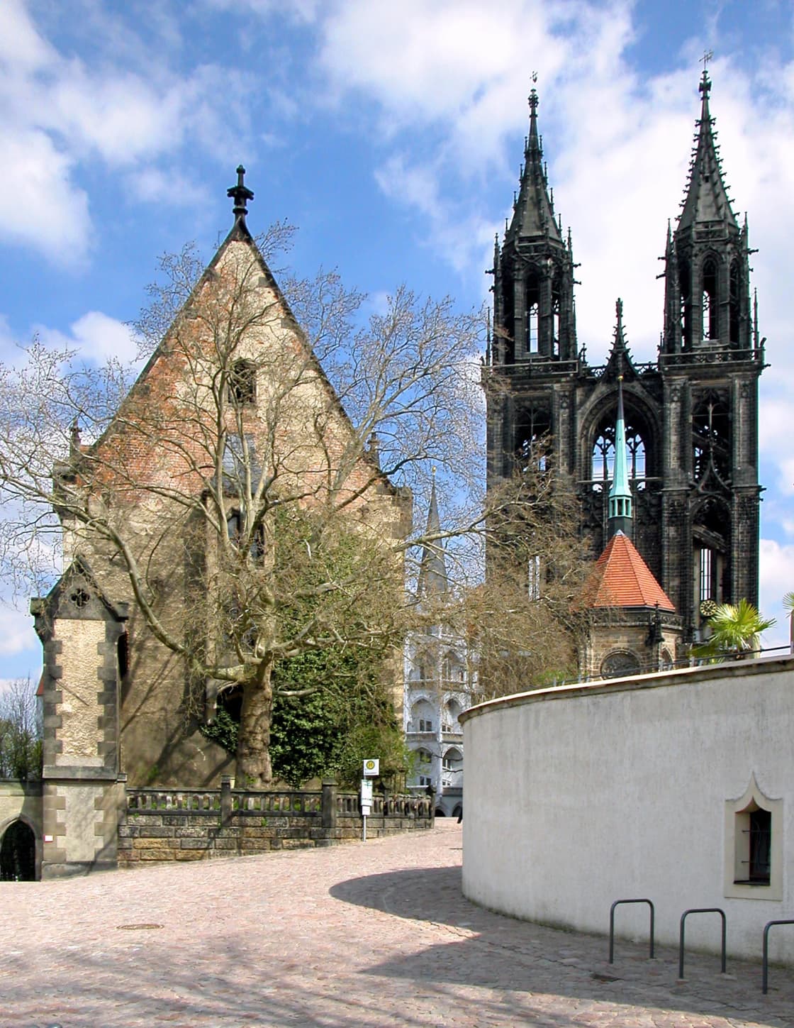 A cobbled ramp climbing toward Meissen Cathedral, its dark openwork Gothic spires rising above a stone gable and a curved castle wall