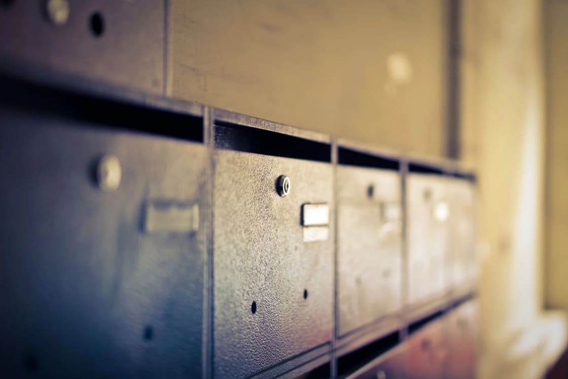 A row of vintage metal mailbox doors with keyholes, receding into soft focus