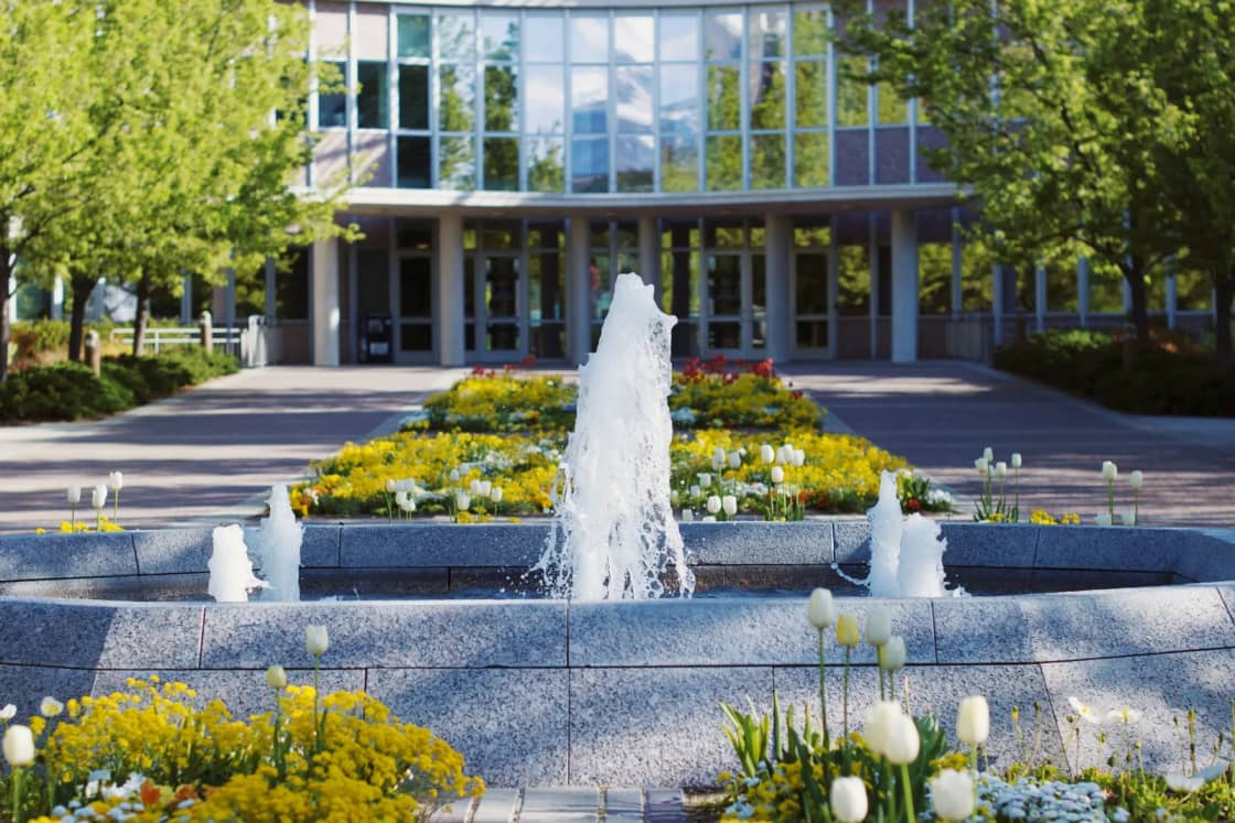 A fountain and spring tulip beds in front of the glass entrance of the Abraham Smoot Building on the BYU campus