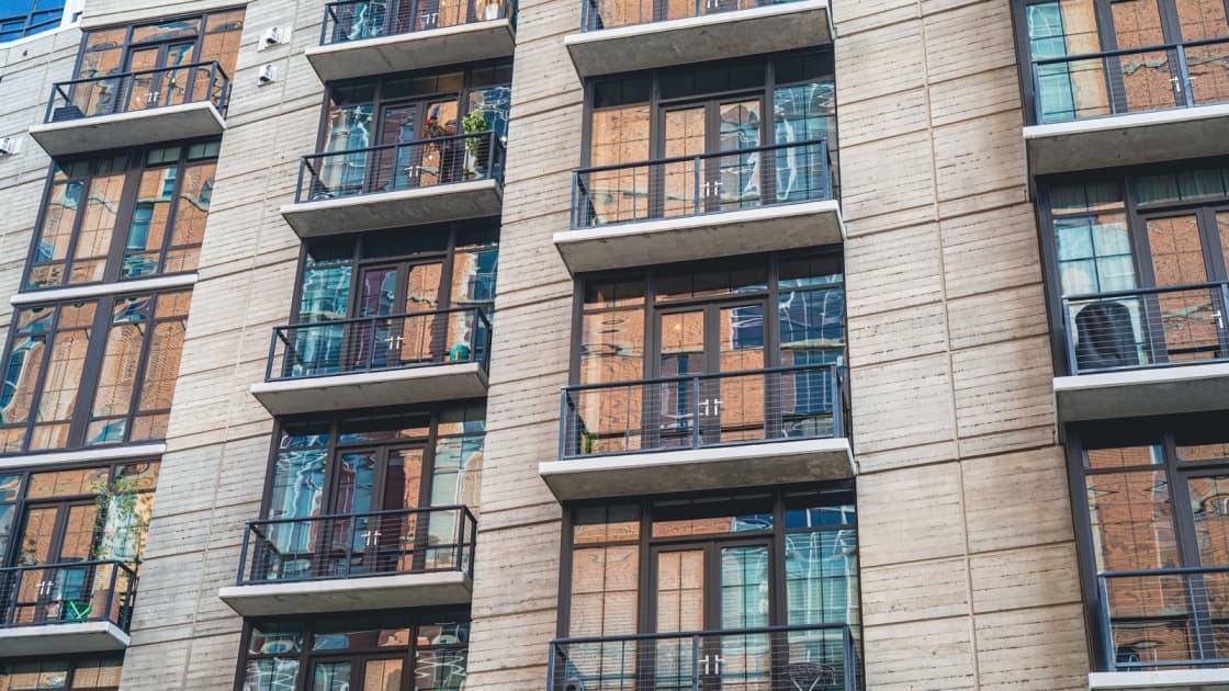 The facade of a modern apartment building with rows of balconies and tall windows