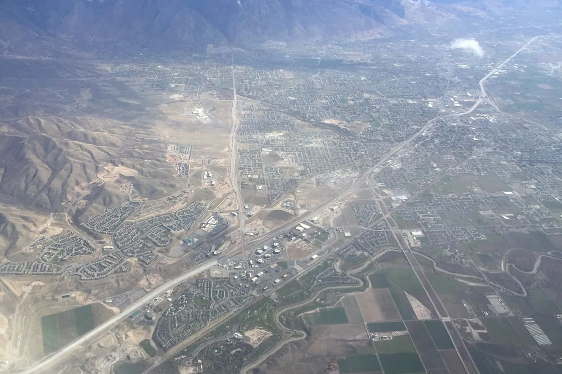 Aerial view of Lehi, American Fork and Highland spreading along Interstate 15 below the Wasatch foothills.