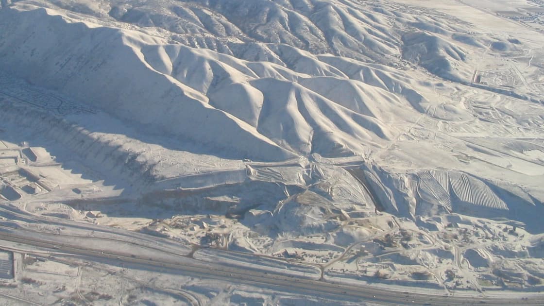 The snow-covered ridges of the Traverse Mountains between Salt Lake and Utah counties seen from the air, with roads curving along their base