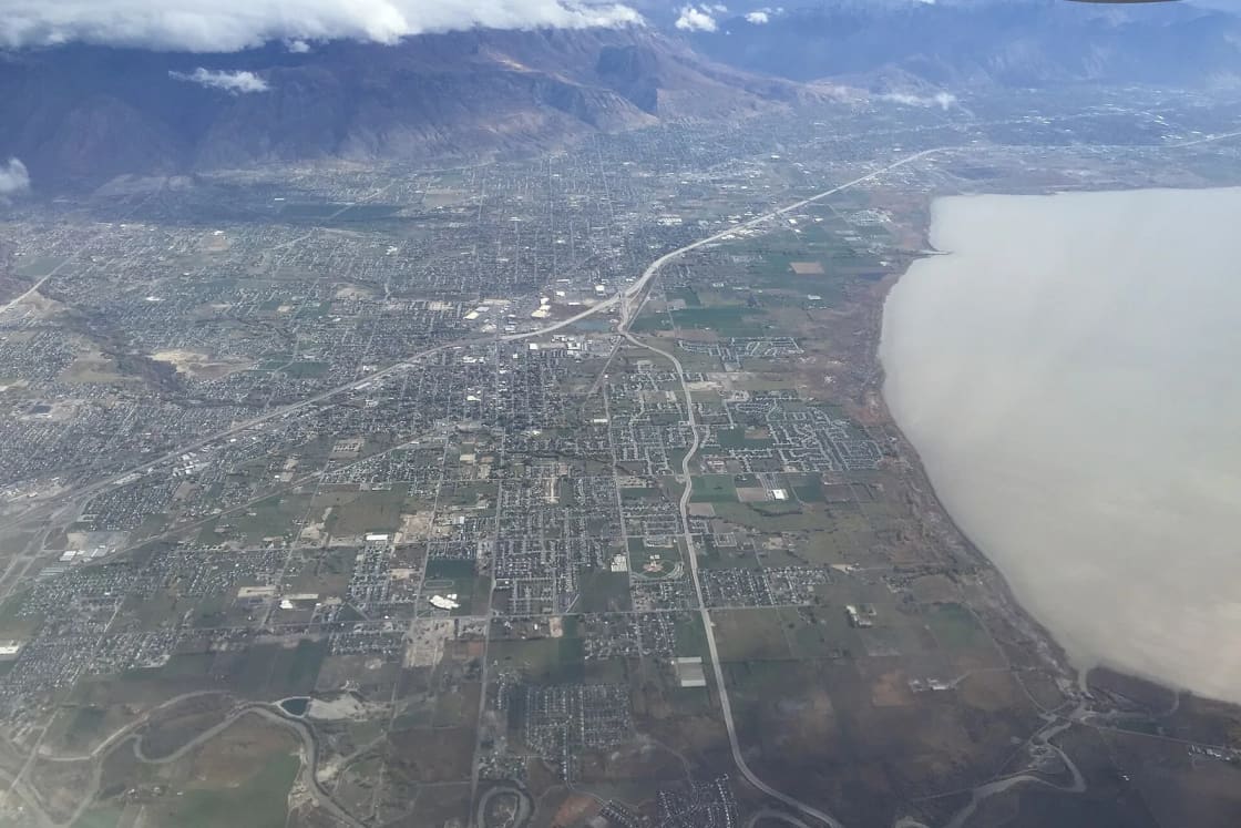 Aerial view of north Utah County neighborhoods along Interstate 15 beside Utah Lake, with the Wasatch Range behind.