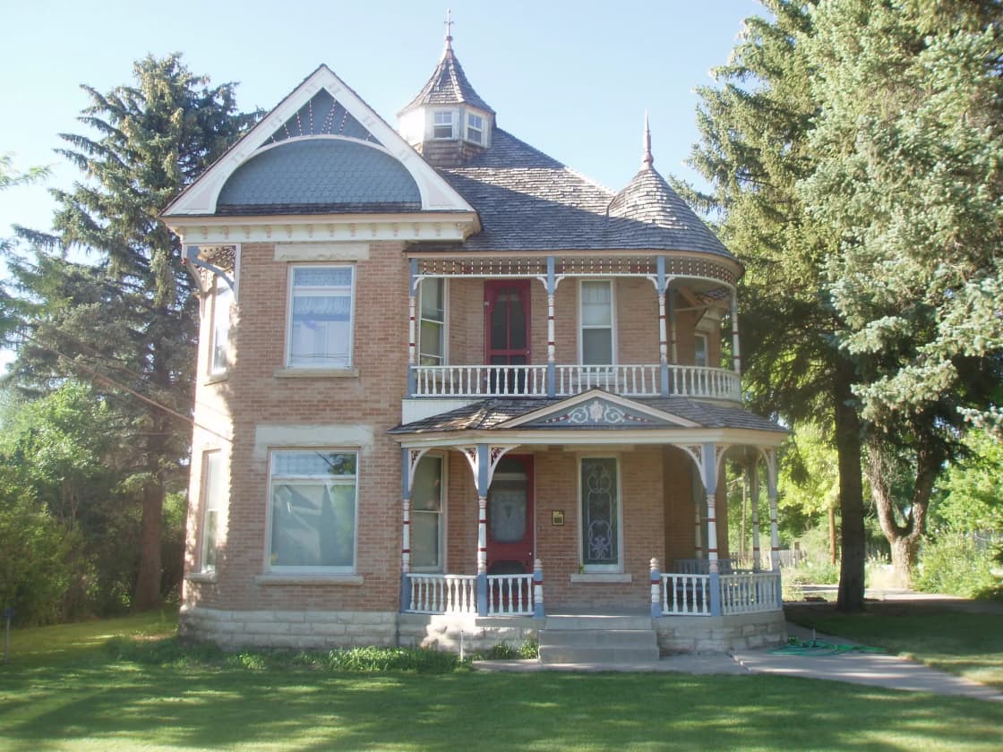 The John Dorius Jr. House in Ephraim, a two-story brick Queen Anne home from 1897 with a turret, white porch railings and tall evergreens beside a green lawn