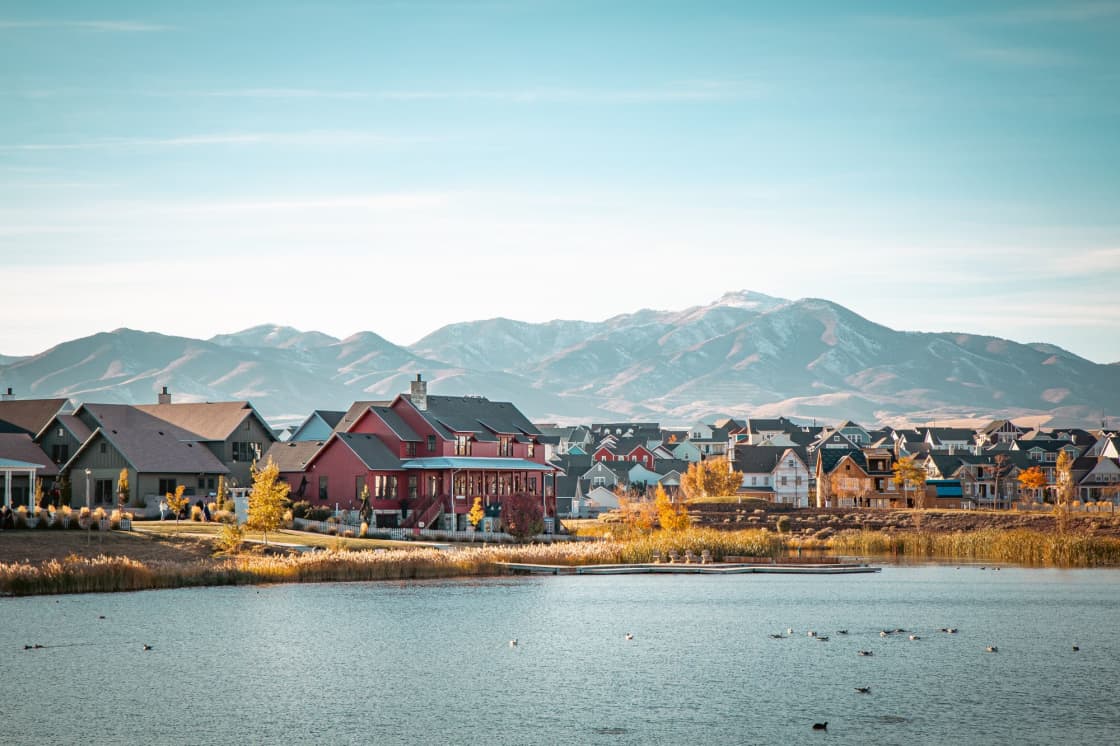 Houses along a lakeshore with autumn trees and a dry mountain range behind