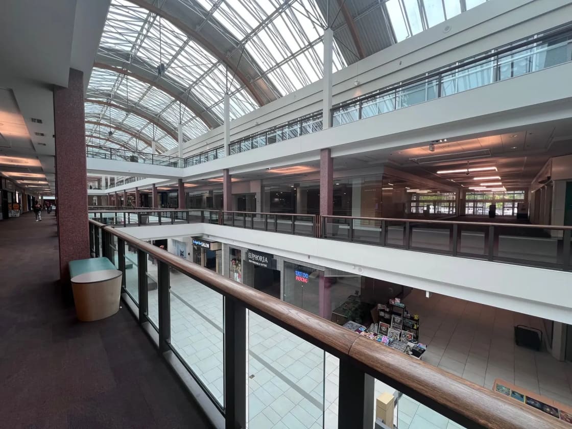 A spacious indoor shopping mall lit by a skylight roof