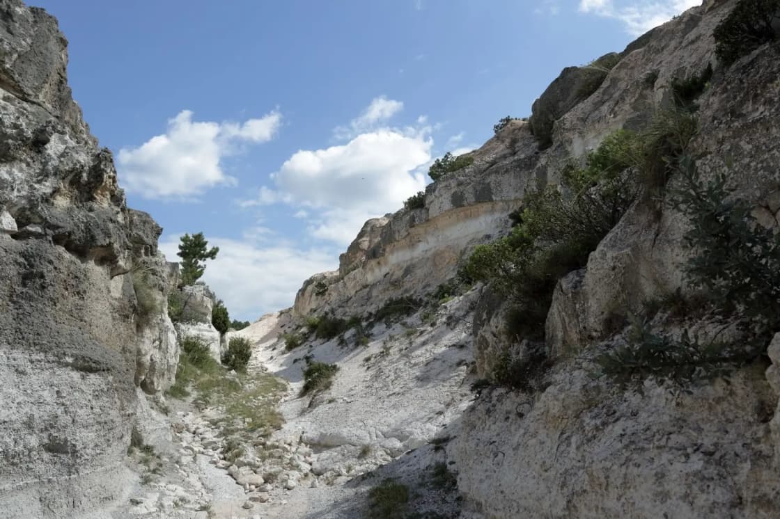 A rocky canyon mouth rising out of dry foothills under a bright sky