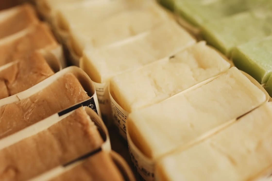 Pale handmade soap bars wrapped in printed paper and stacked in rows