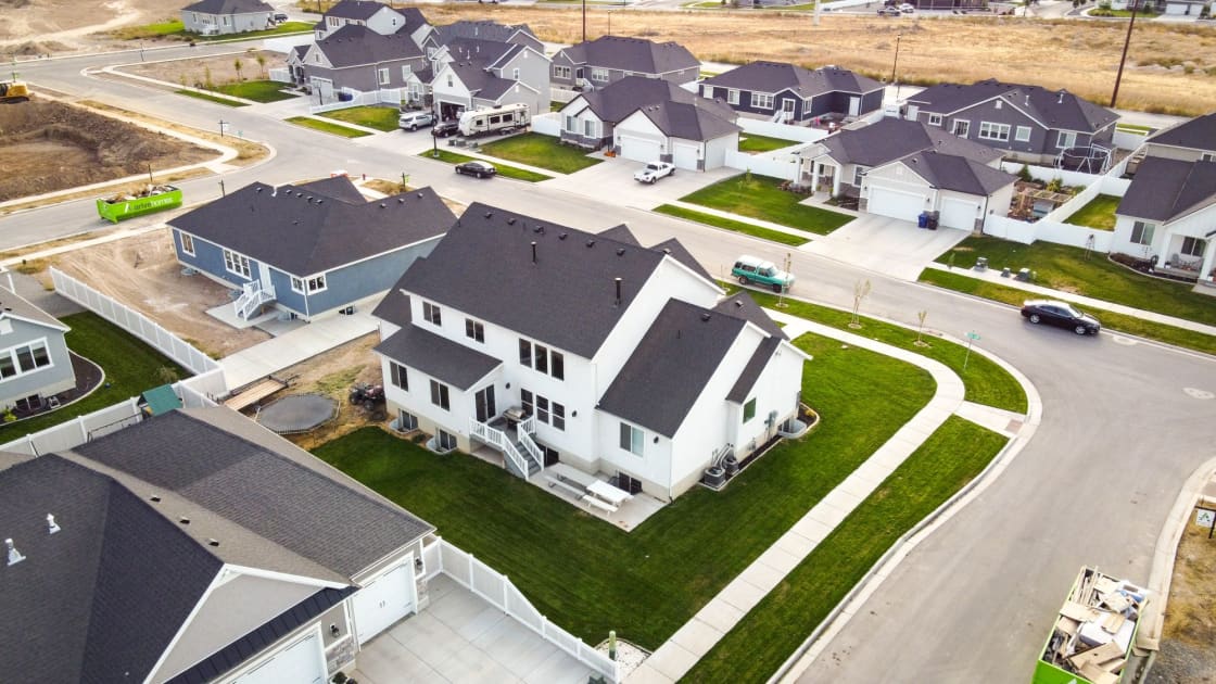 An aerial view of a new subdivision with vinyl fencing and dry ground at the construction edge