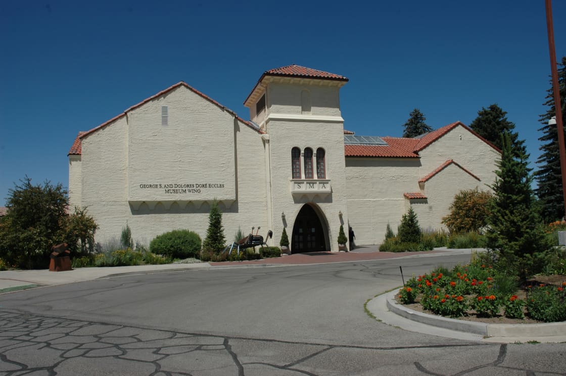 Cream stucco museum building with a red tile roof and arched entrance under a deep blue sky