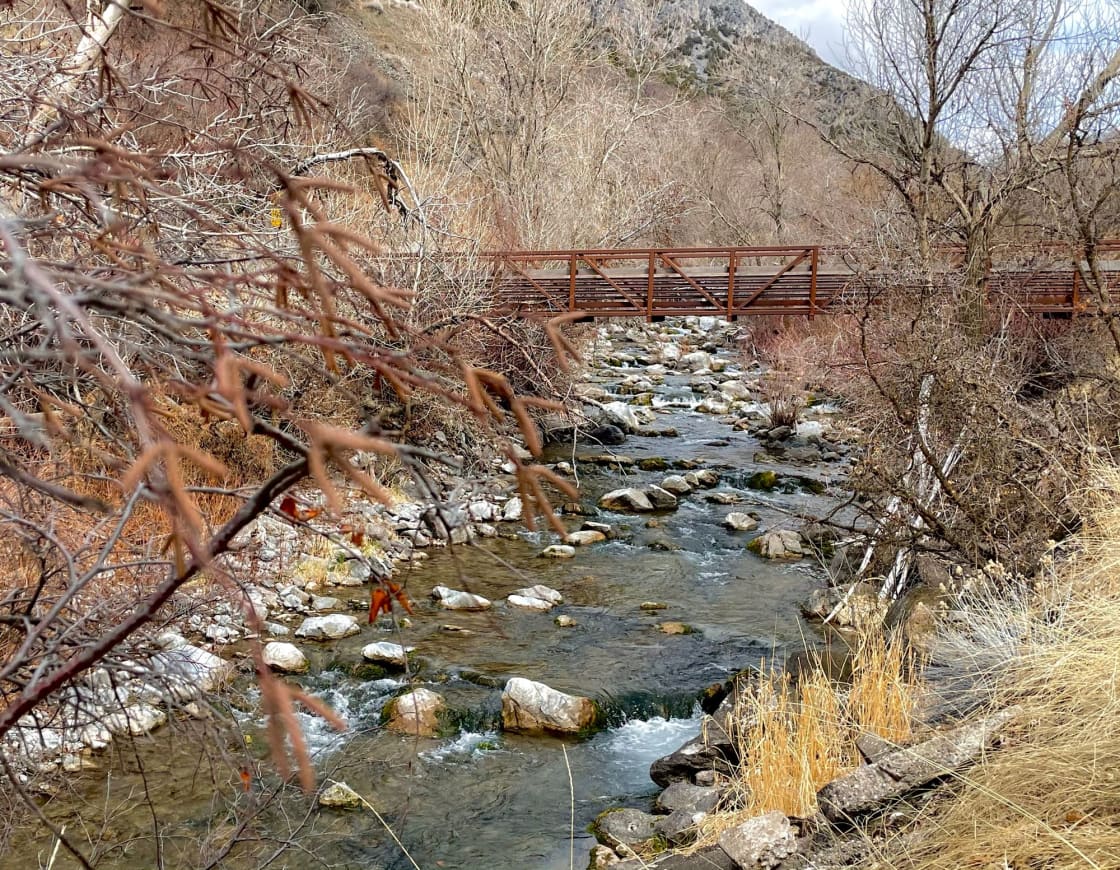 A rocky creek running under a steel footbridge at the mouth of a canyon in late autumn