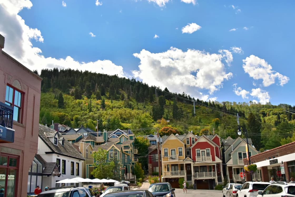 Colorful historic houses climbing the hillside above Park City's Main Street on a sunny summer day, ski runs green behind them