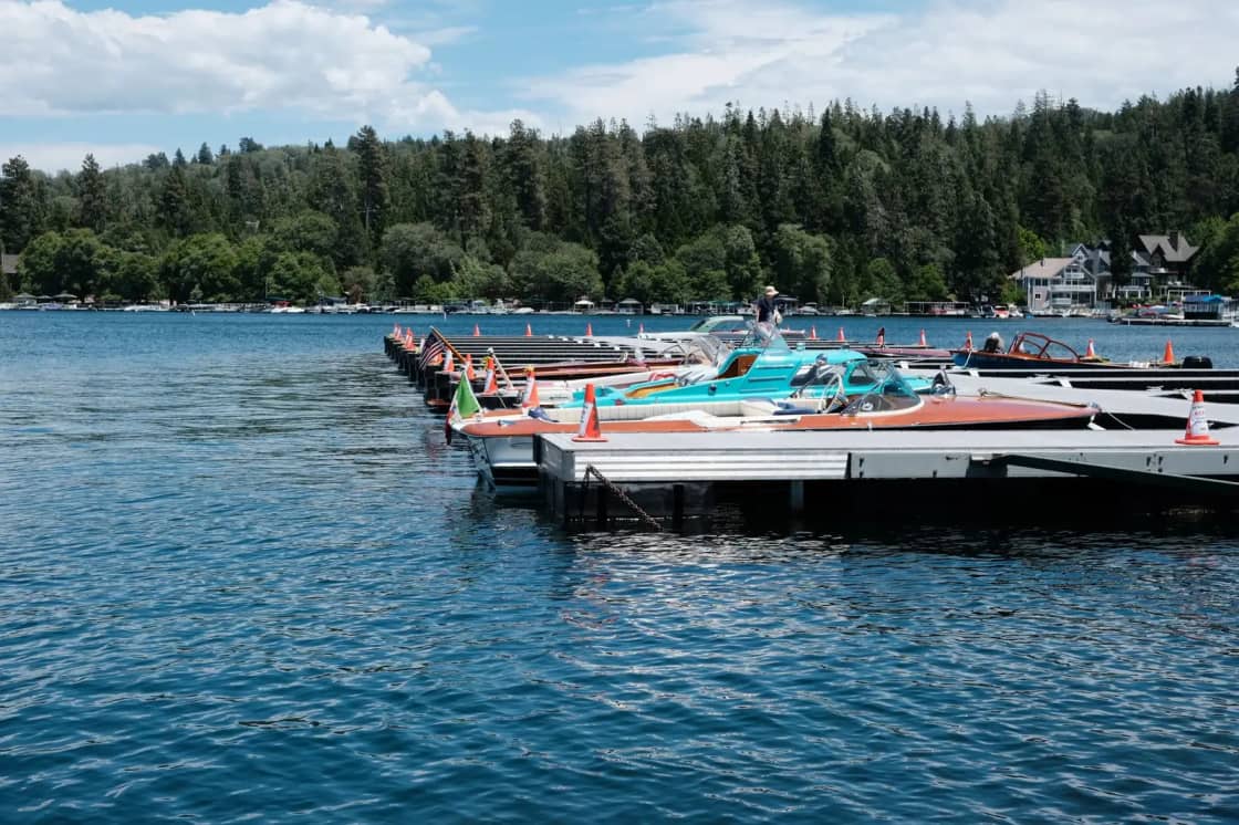Peaceful view of boats docked at a lakeside surrounded by lush forest under a clear sky