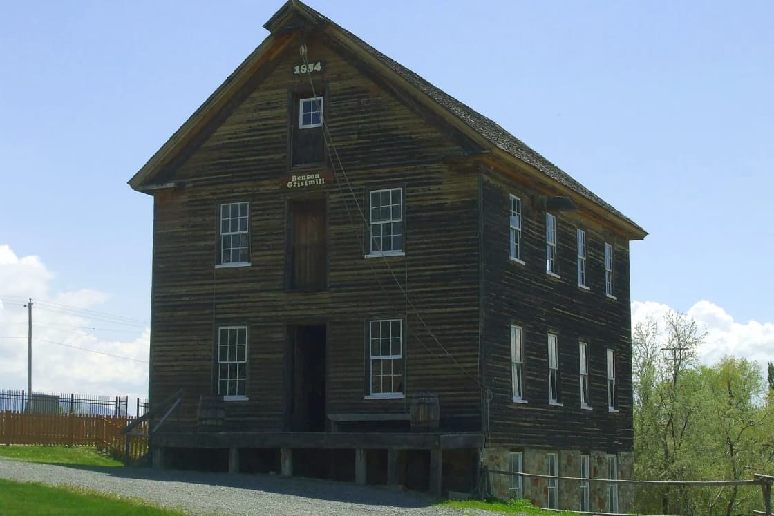 The weathered wooden Benson Grist Mill, built in 1854, stands three stories tall under a spring sky.