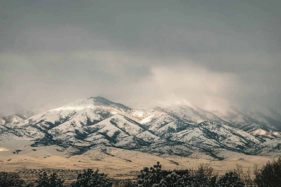 Snow-dusted mountains rising above a high desert valley in Utah, low winter clouds hanging over the ridgeline