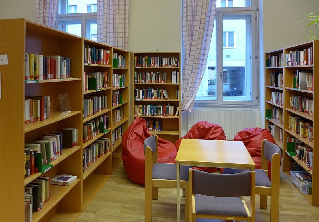 A school library with study tables, chairs and bookshelves along the walls