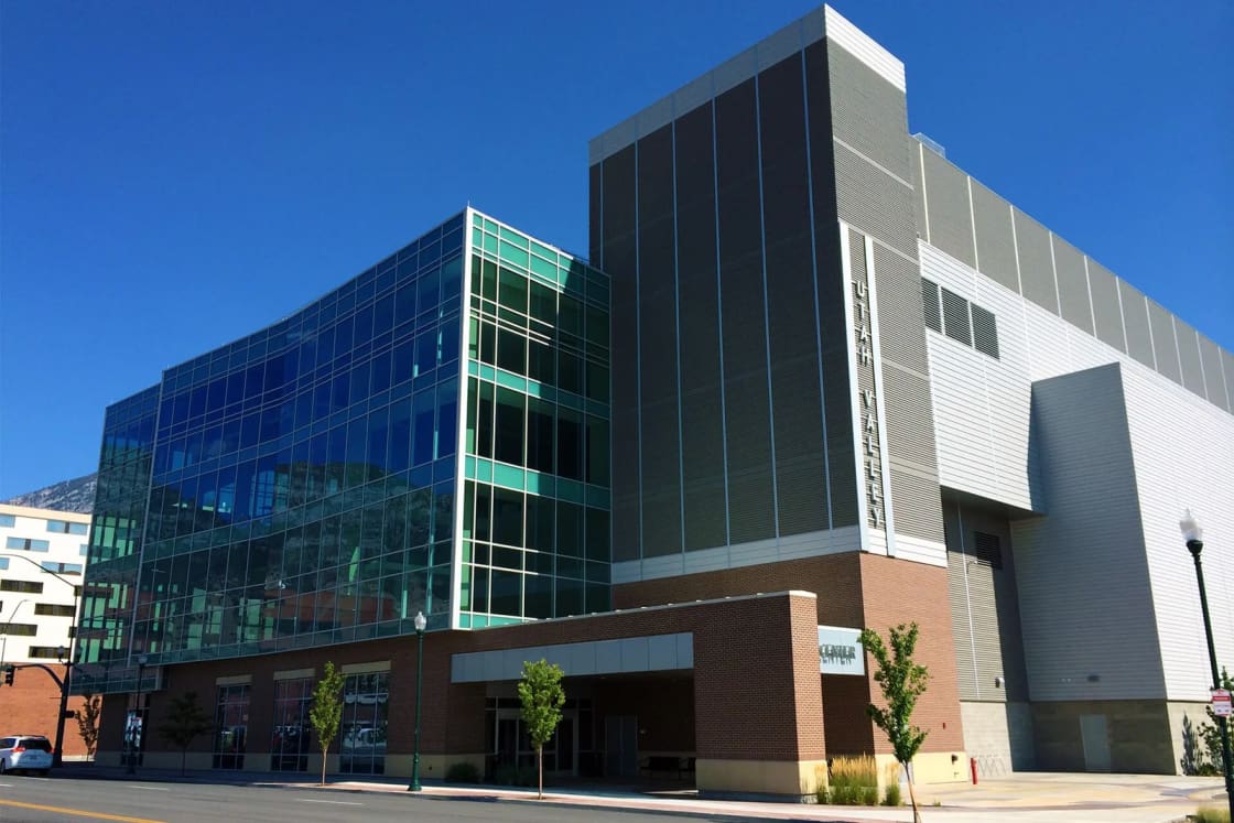 The glass and gray-panel side of the Utah Valley Convention Center in downtown Provo under a clear blue sky.