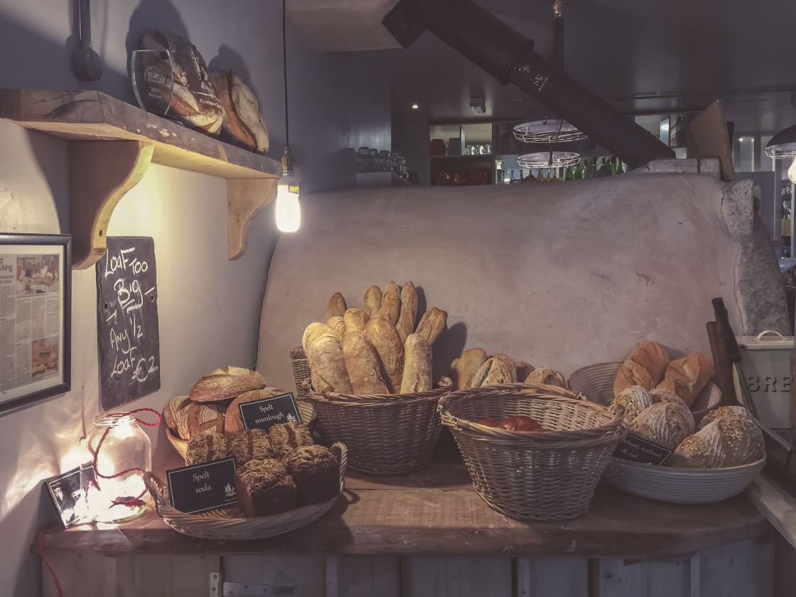 Baskets of crusty artisan loaves on a bakery counter beneath a warm hanging light