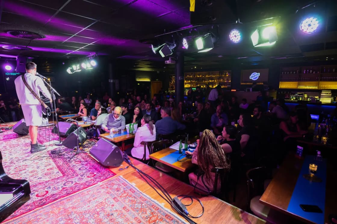 A band performing to a packed crowd in a small, low-lit club room