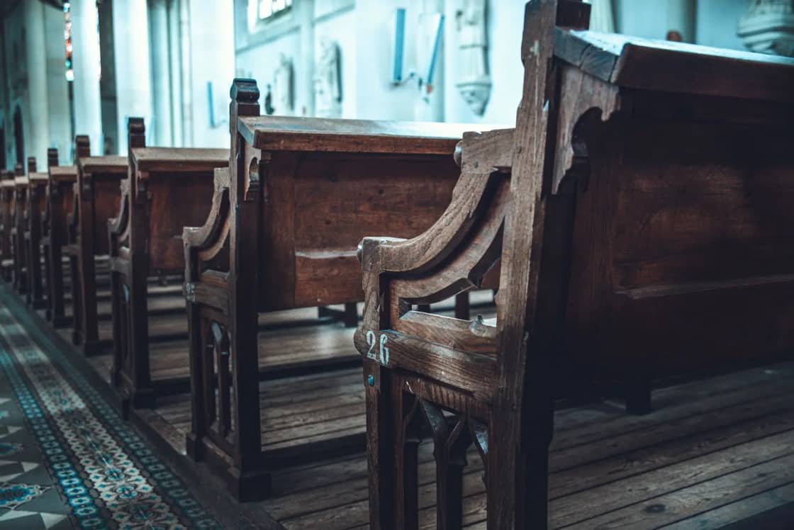 A serene view of traditional wooden church pews aligned in a sunlit interior