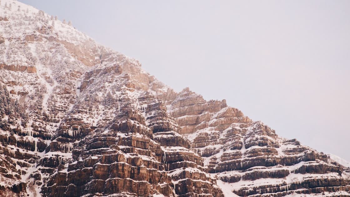 Snow-dusted limestone cliffs rising in tiers above Provo Canyon under a pale winter sky