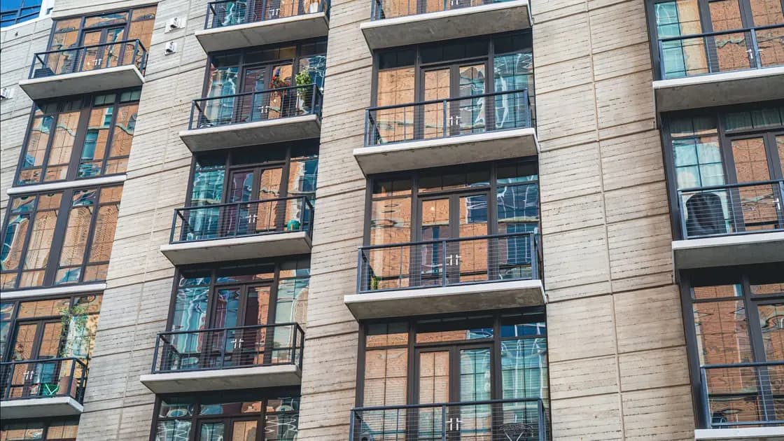 Rows of glass-railed balconies on the facade of a modern apartment building
