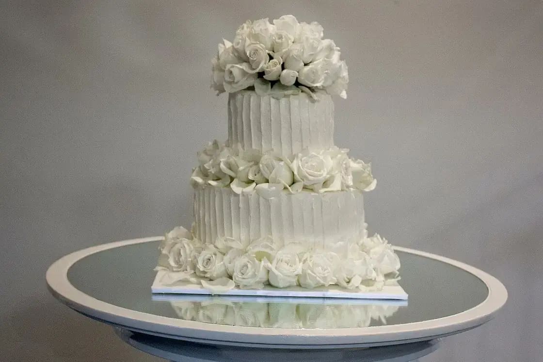 A two-tier buttercream wedding cake decorated with fresh white roses