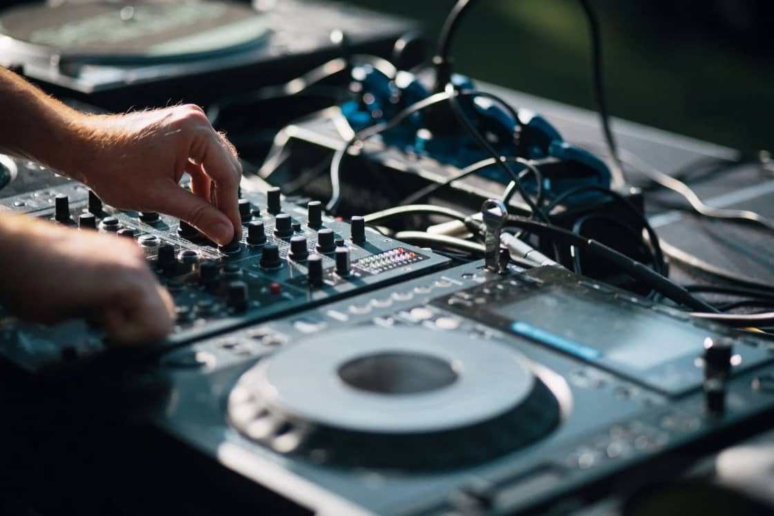 Hands adjusting the knobs and jog wheels of a DJ controller.