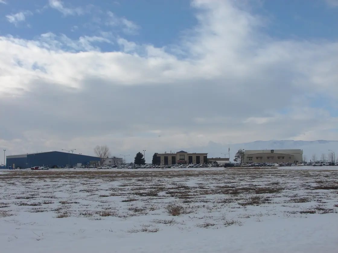Open ground on the west side of Provo with airport buildings low on the horizon and the Lake Mountains beyond