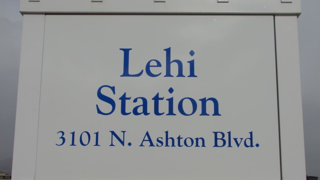 The Lehi Station sign, reading Lehi Station, 3101 N. Ashton Blvd., in blue letters on a white panel
