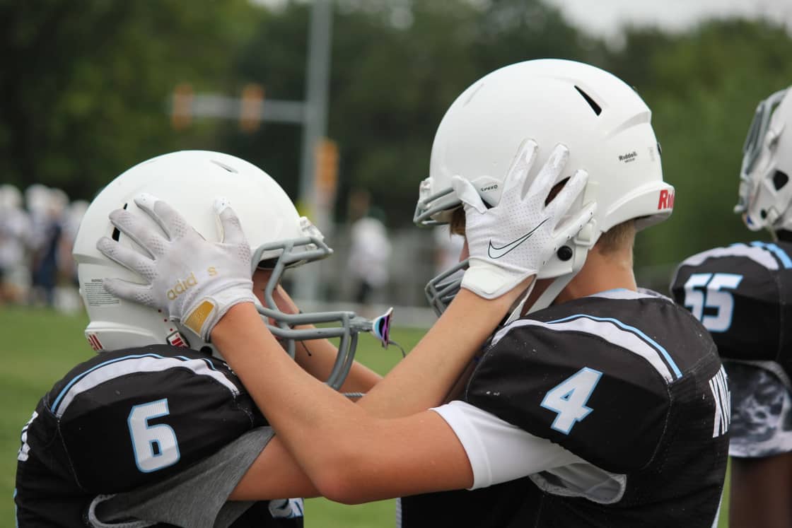 Two young football players in white helmets facing each other before a game