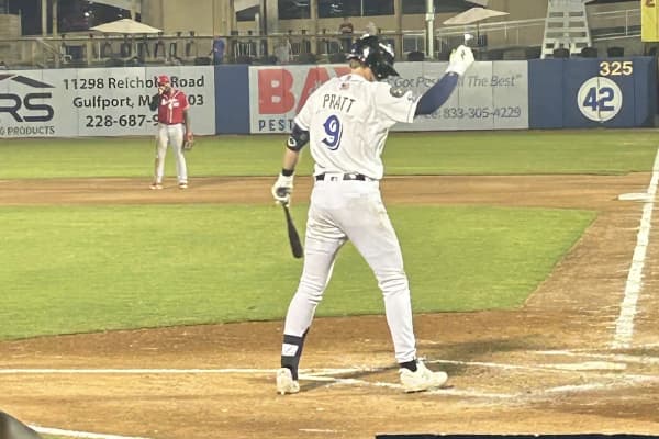 Cooper Pratt, wearing a white Biloxi Shuckers jersey with PRATT and the number 9 on the back, adjusting his batting helmet at the plate during a night game in 2025