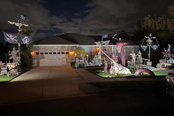 The whole Gibb front yard at night, with pirate masts and Jolly Roger flags on both ends, Kraken tentacles and a wrecked ship in the middle
