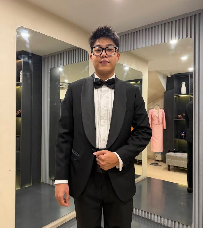 A black tuxedo with shawl lapels and a pleated shirt, designed by Unlim Tailor.