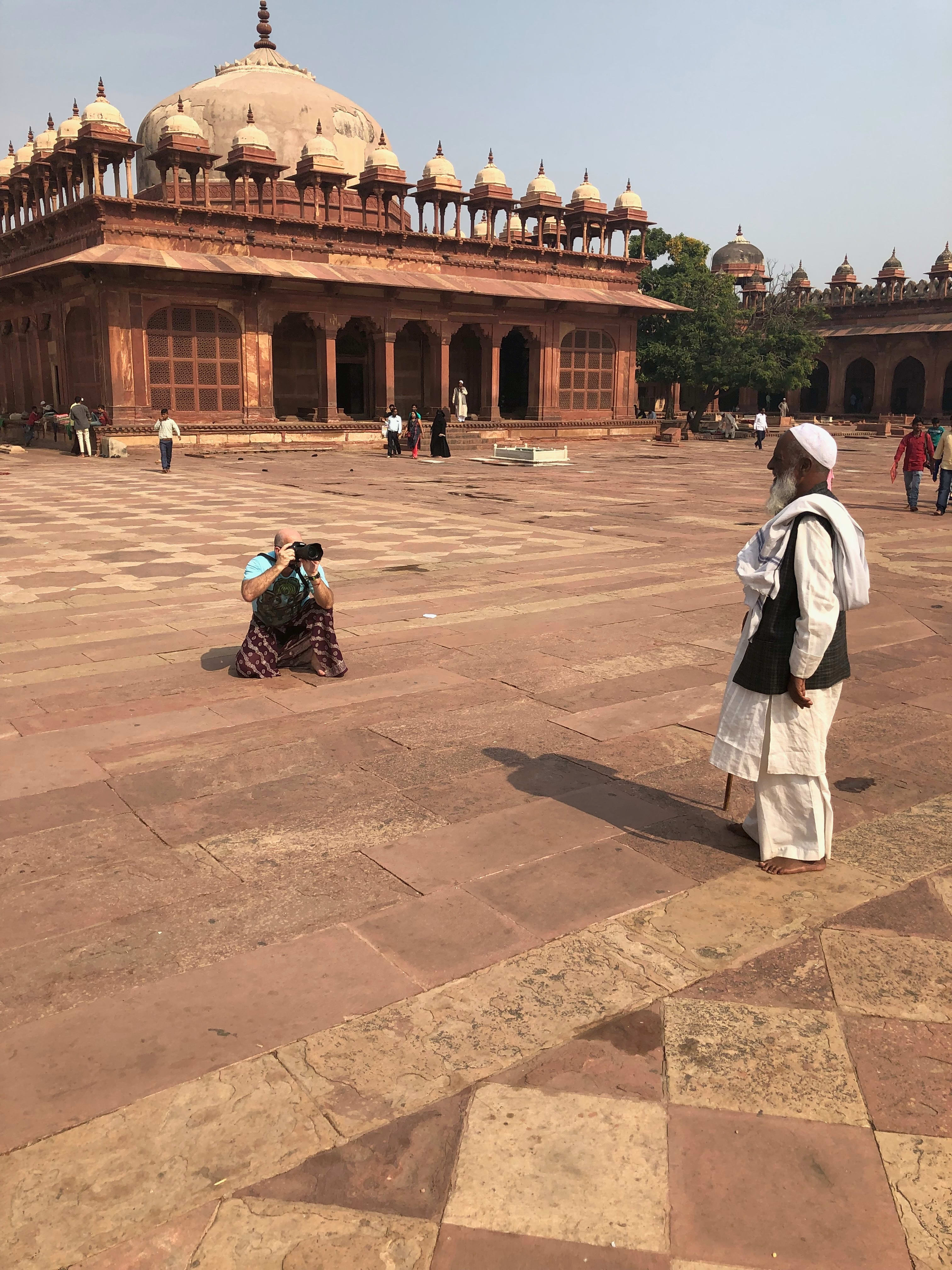 Visitors crossing the sandstone courtyard beside the prayer-hall architecture at Jama Masjid, Fatehpur Sikri.