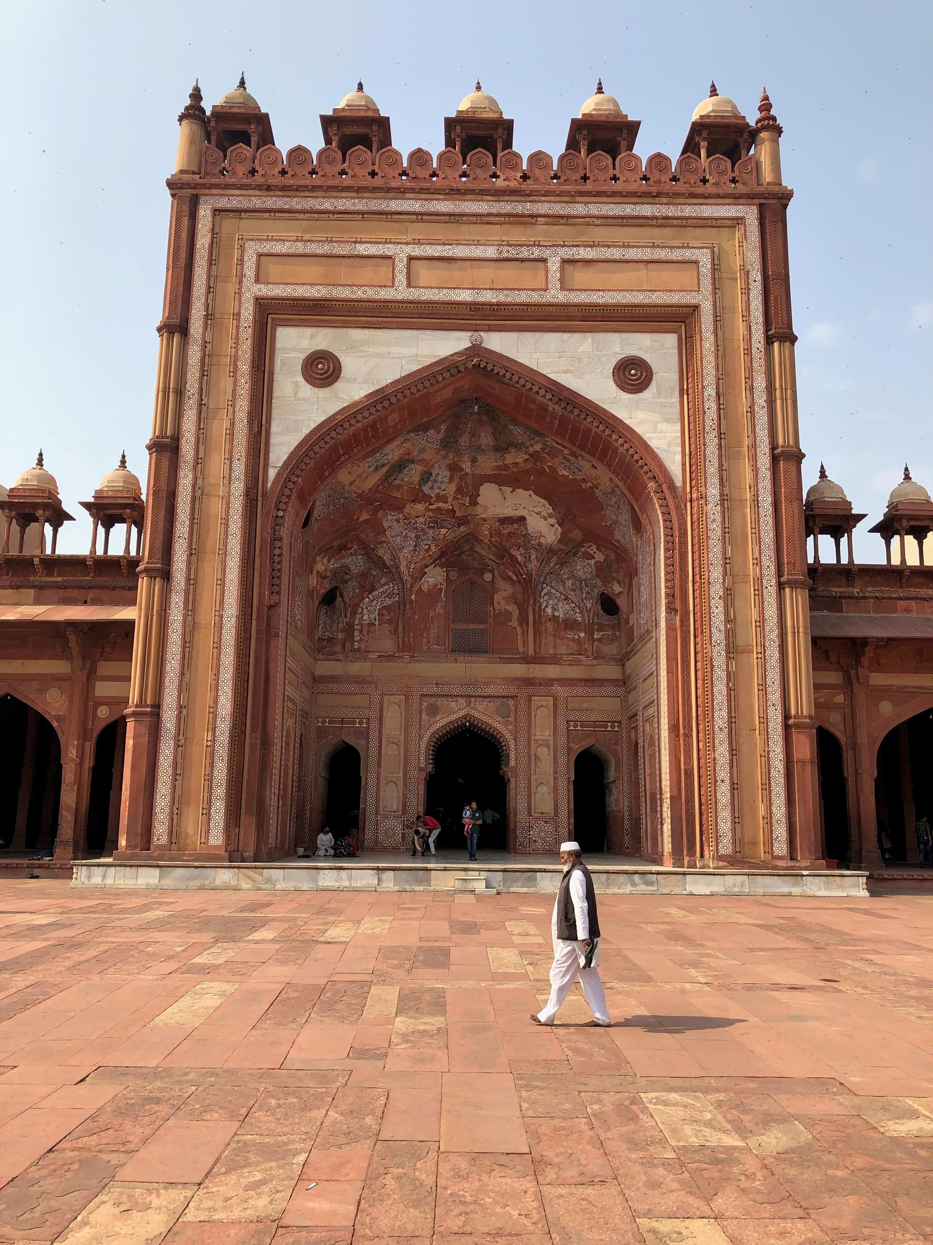 Red sandstone monumental architecture and visitors inside the Jama Masjid precinct, Fatehpur Sikri.