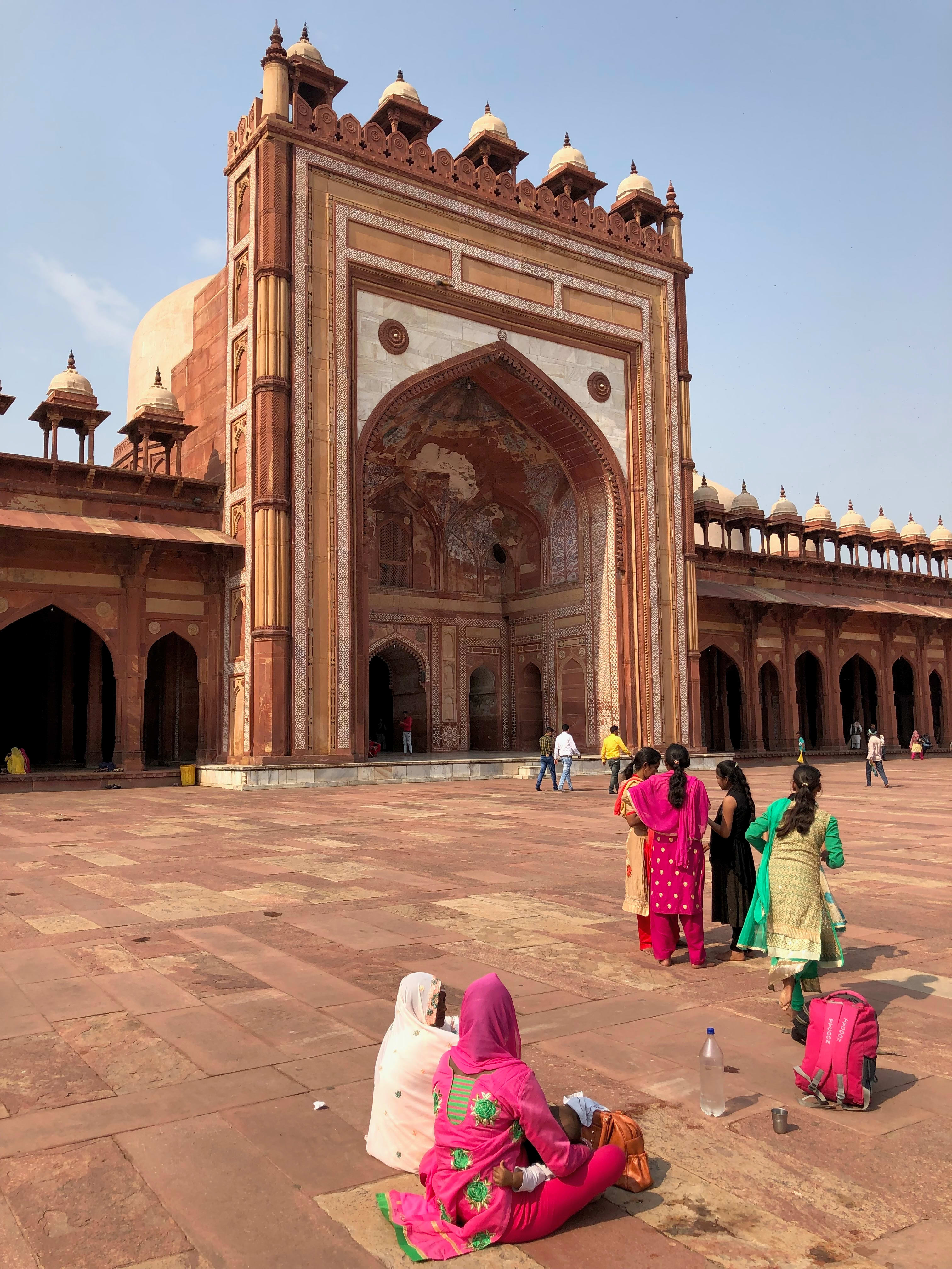 Visitors in colourful clothing near the large red sandstone prayer-hall portal of Jama Masjid, Fatehpur Sikri.