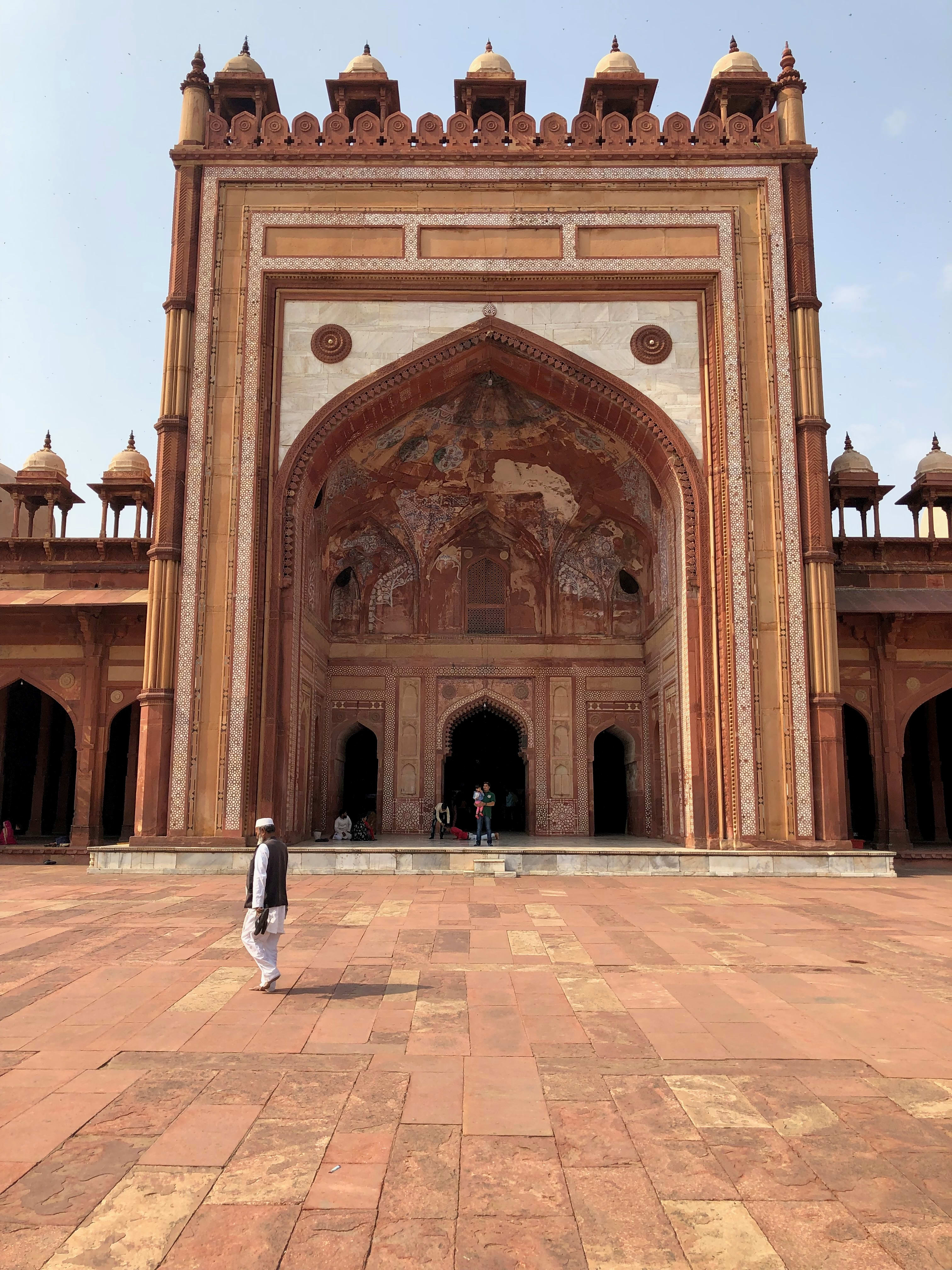 A visitor before the monumental red sandstone prayer-hall portal at Jama Masjid, Fatehpur Sikri.