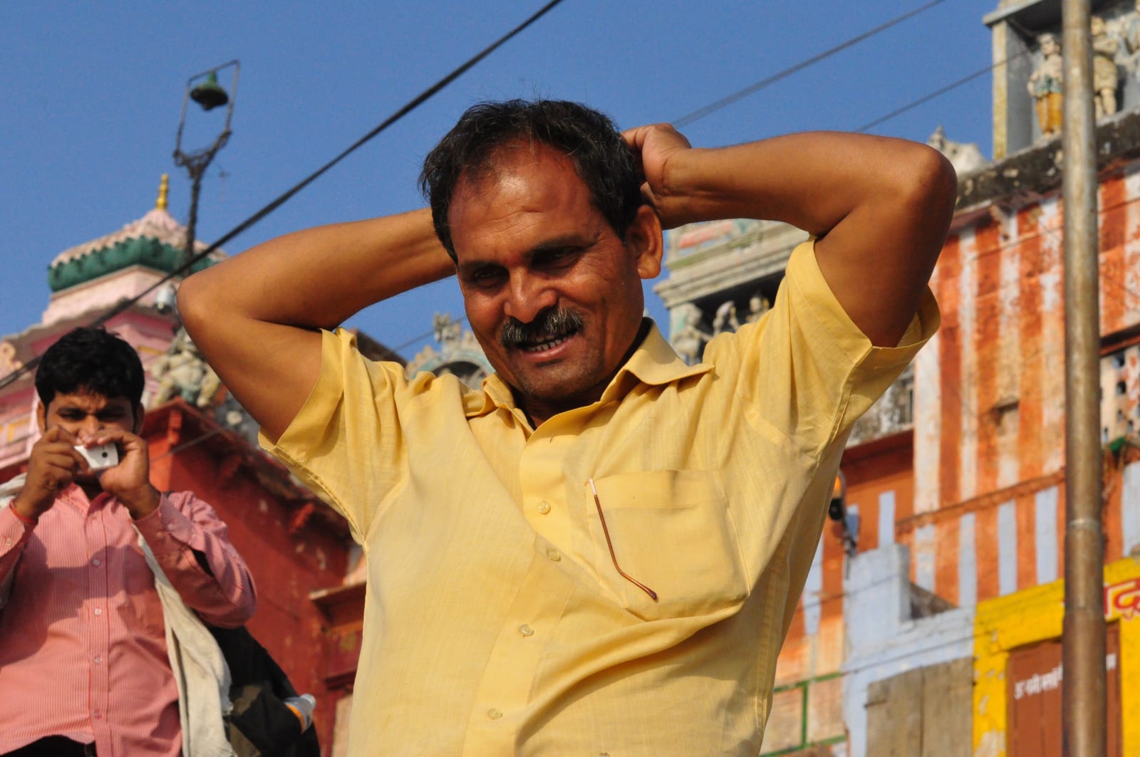 Pandu in a yellow shirt, his hands raised behind his head, beside the riverfront.