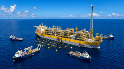Large newbuild FPSO vessel at sea in tropical daylight with a flare boom at the stern