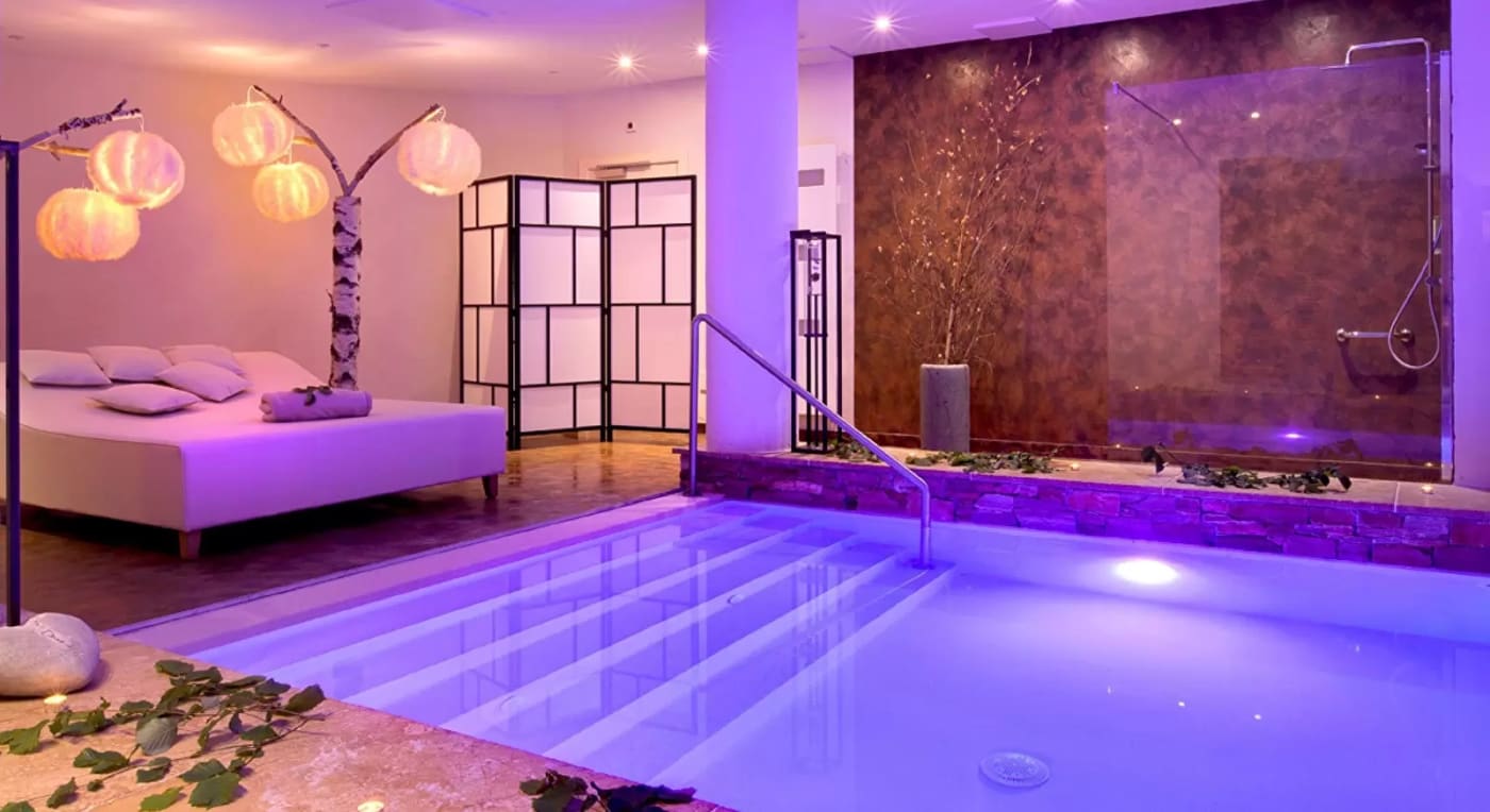 Ein Becken im Spa von La Cheneaudière in Colroy-la-Roche in violettem Licht