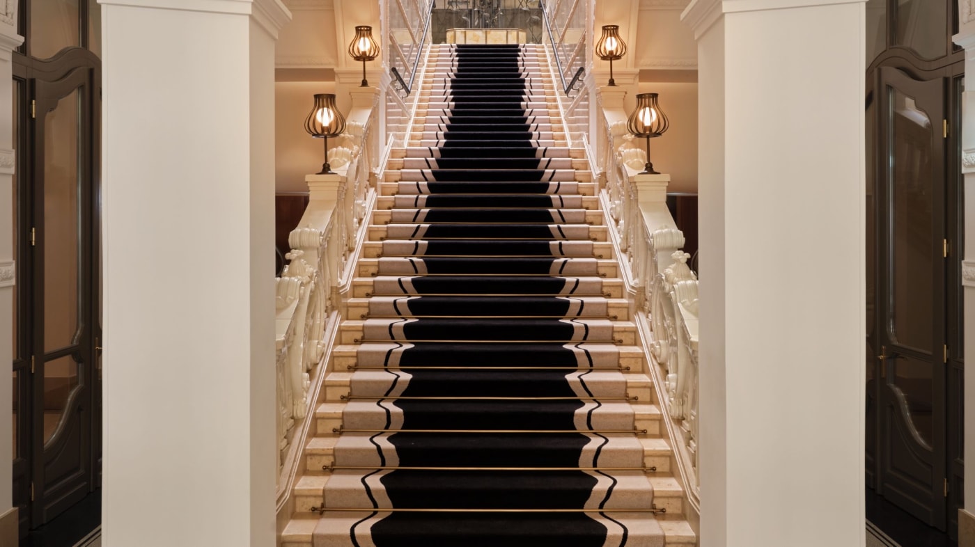 The grand staircase of The St. Regis Budapest, black runner and stone balusters in the Klotild Palace