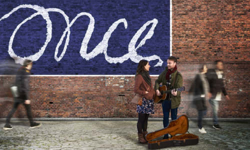 A street scene featuring a busker with a guitar talking to a young woman