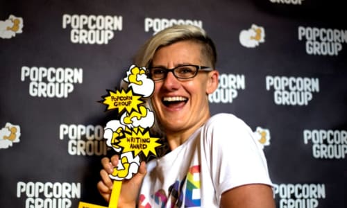 Jennifer Lunn smiling holding up an award for writing