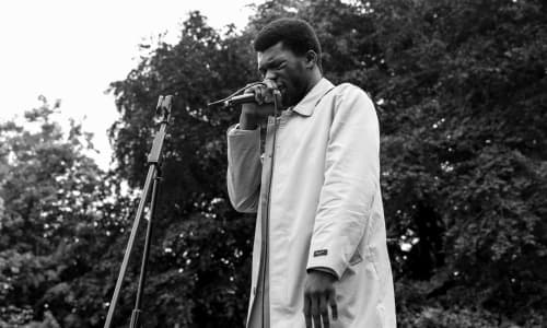 A Black man speaking passionately into a microphone at a Black Lives Matter protest event