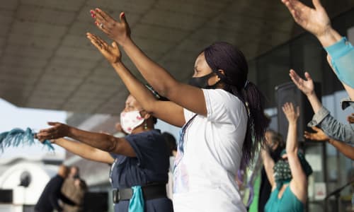 Women wearing masks raising their hands as they dance