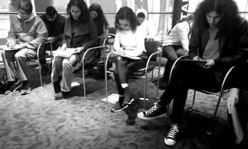 A group of young people sat down writing