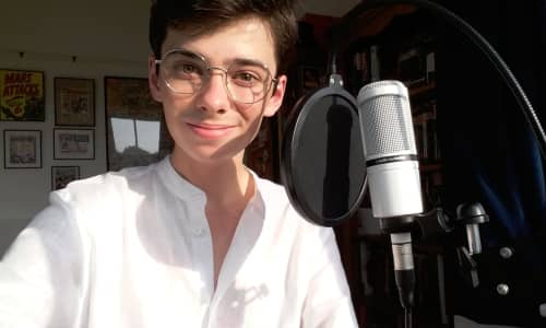 young man in a white shirt sat next to a microphone