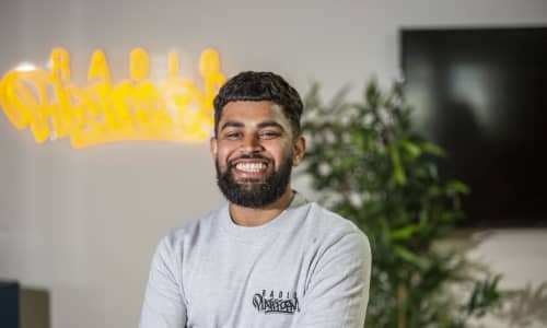 Bablu wears a grey Radio Platfform sweater and is smiling at the camera.