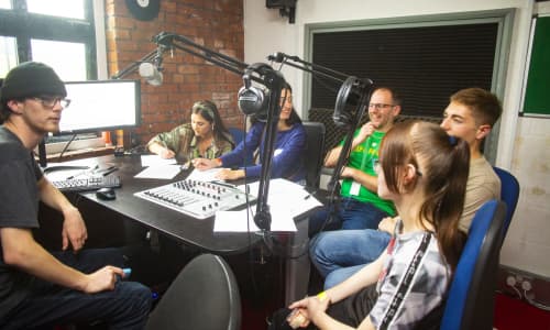 A group of young people sat in a radio station talking